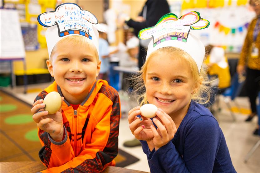 Two girls hold up eggs